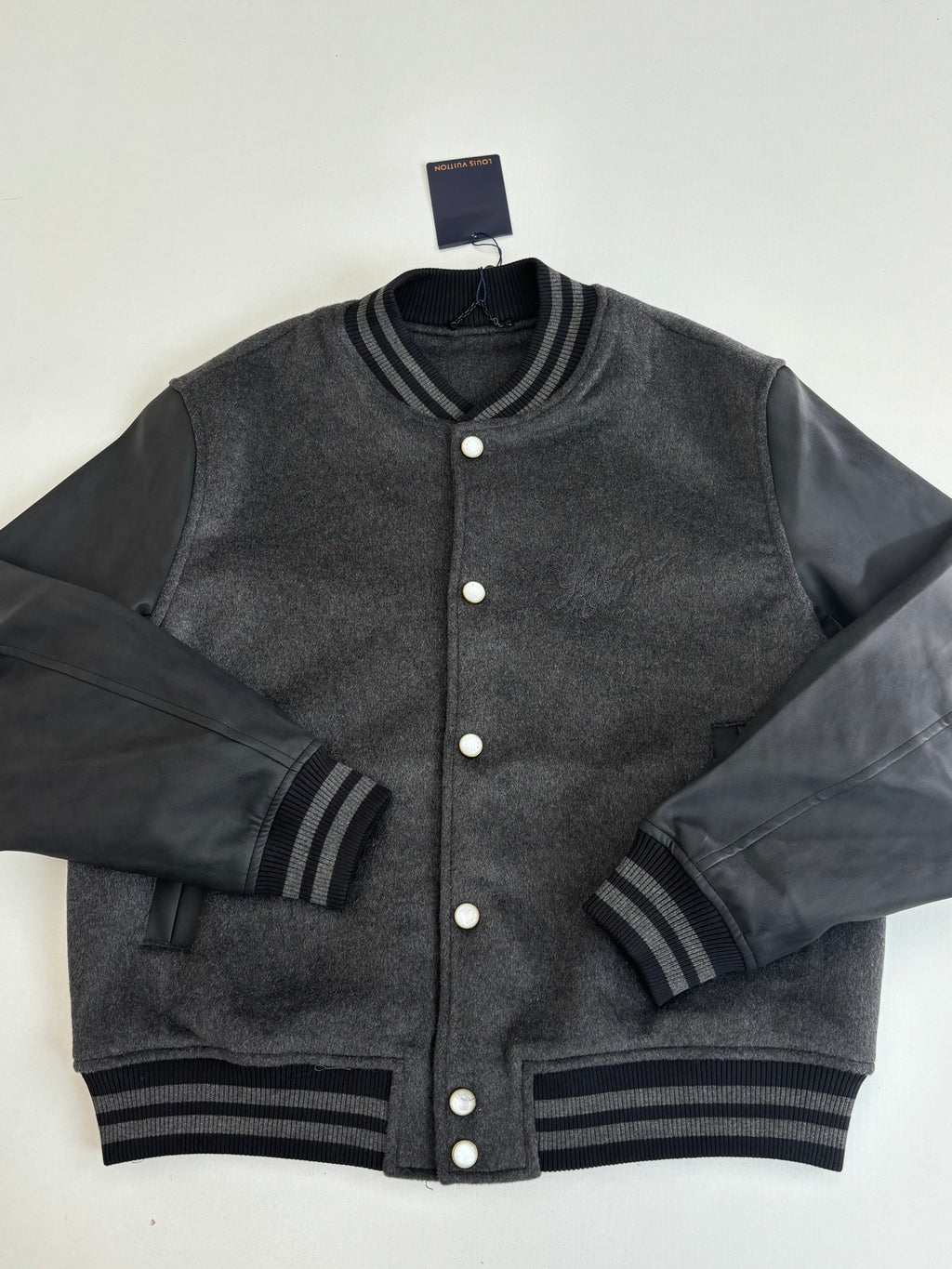 Dark gray varsity jacket with button placket and striped ribbed cuffs