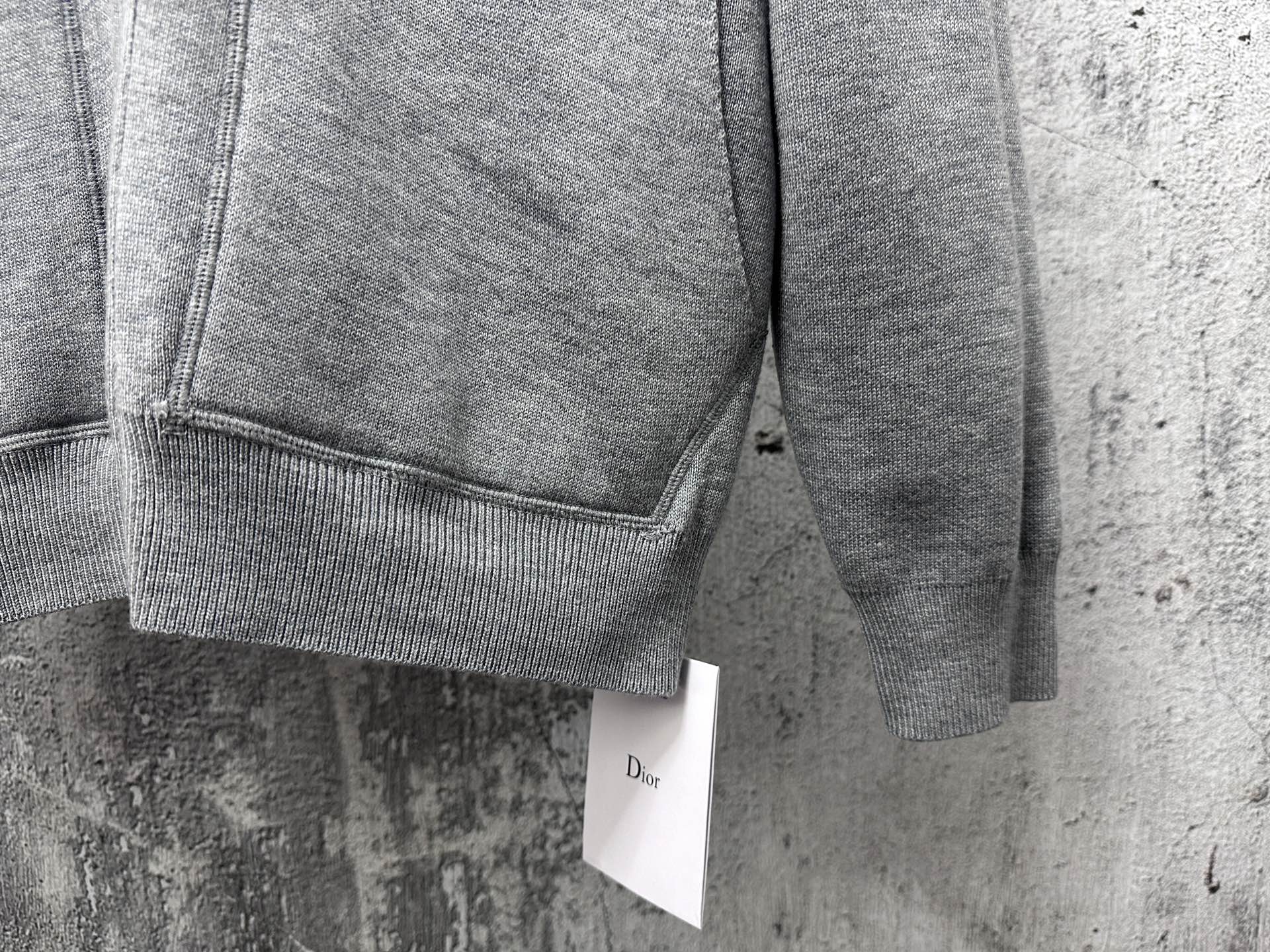 Gray zip-up hoodie close-up of ribbed hem and sleeve cuff