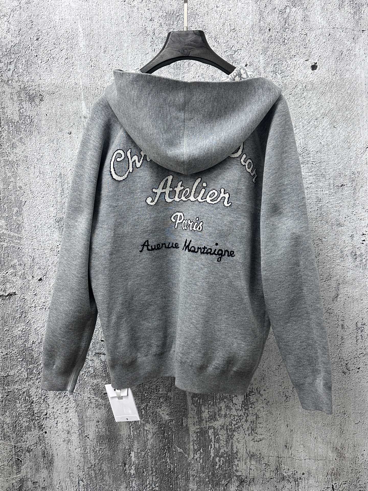 Gray zip-up hoodie with printed “Atelier Paris” text on back