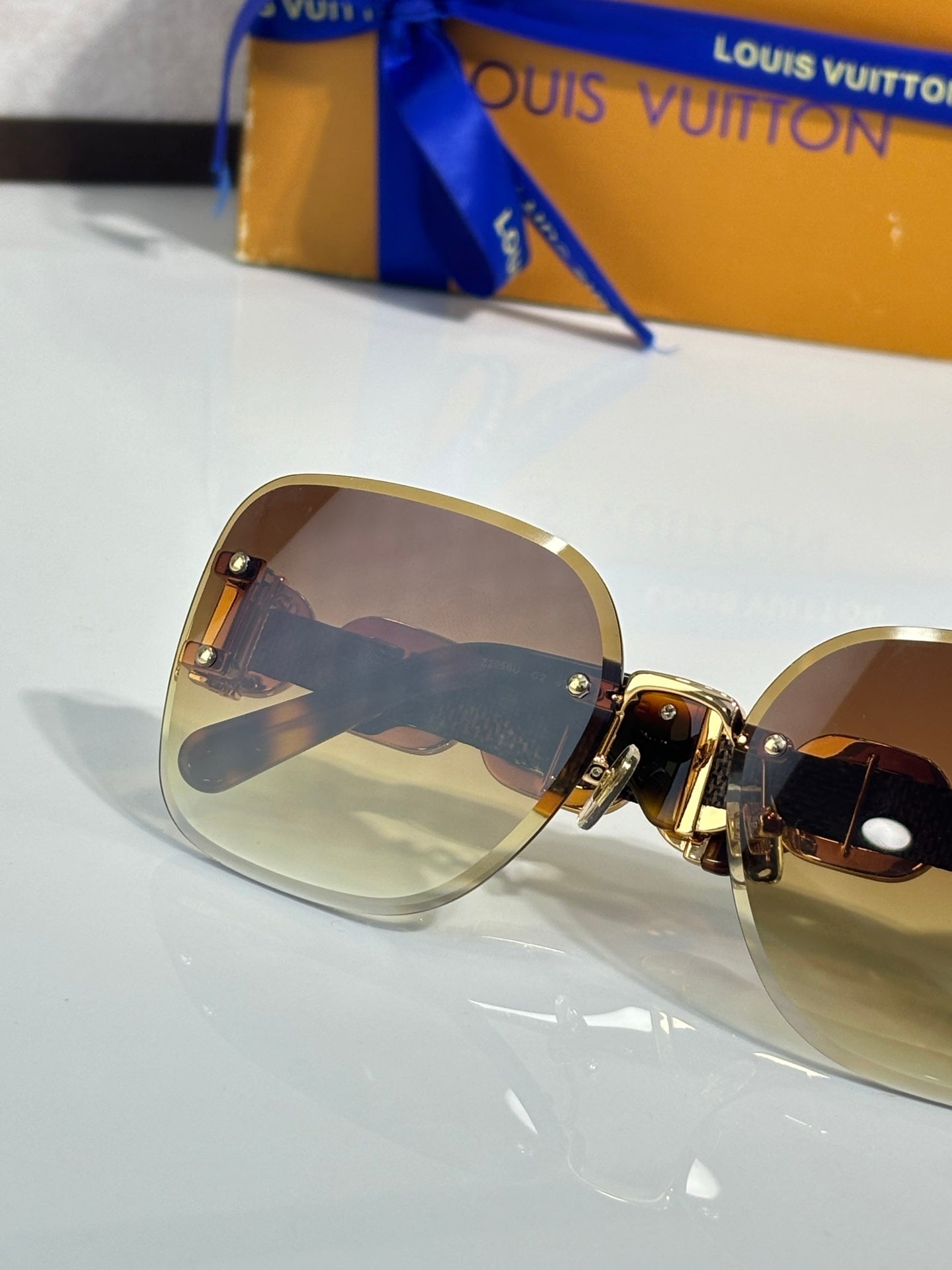 Louis Vuitton sunglasses close-up, tinted lenses, gold frame with dark detail