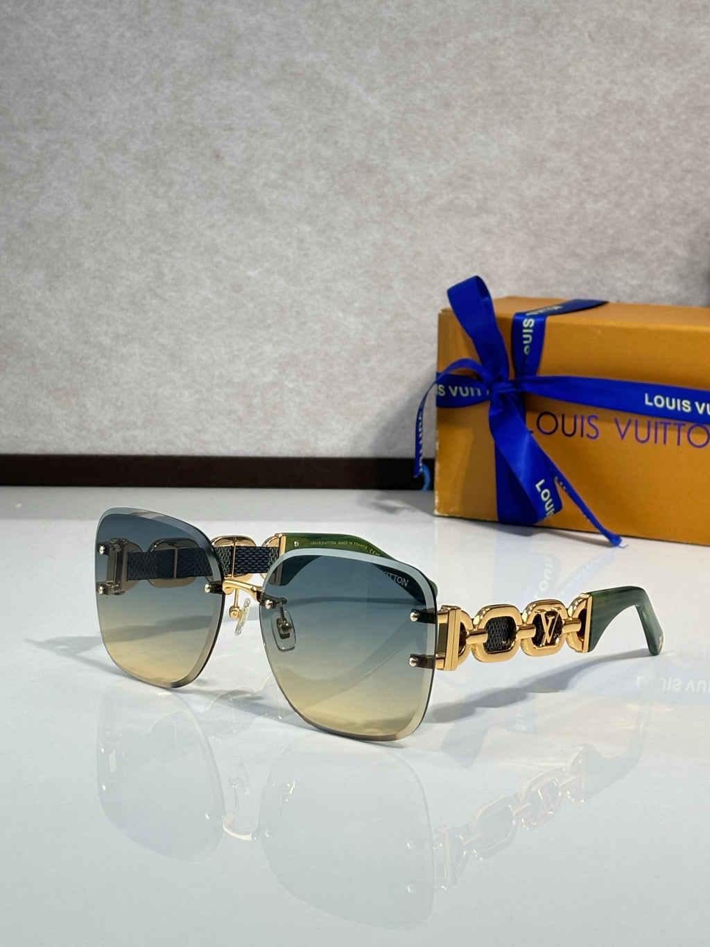 Louis Vuitton sunglasses, green-tinted lenses, black frame, gold logo temple detail