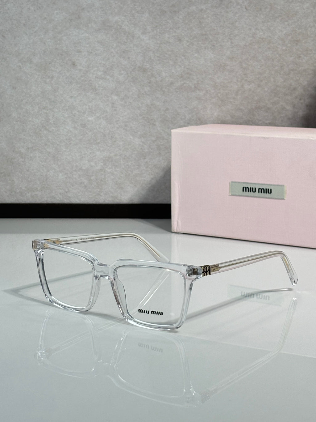 Clear rectangular eyeglasses with metal hinges and Miu Miu logo