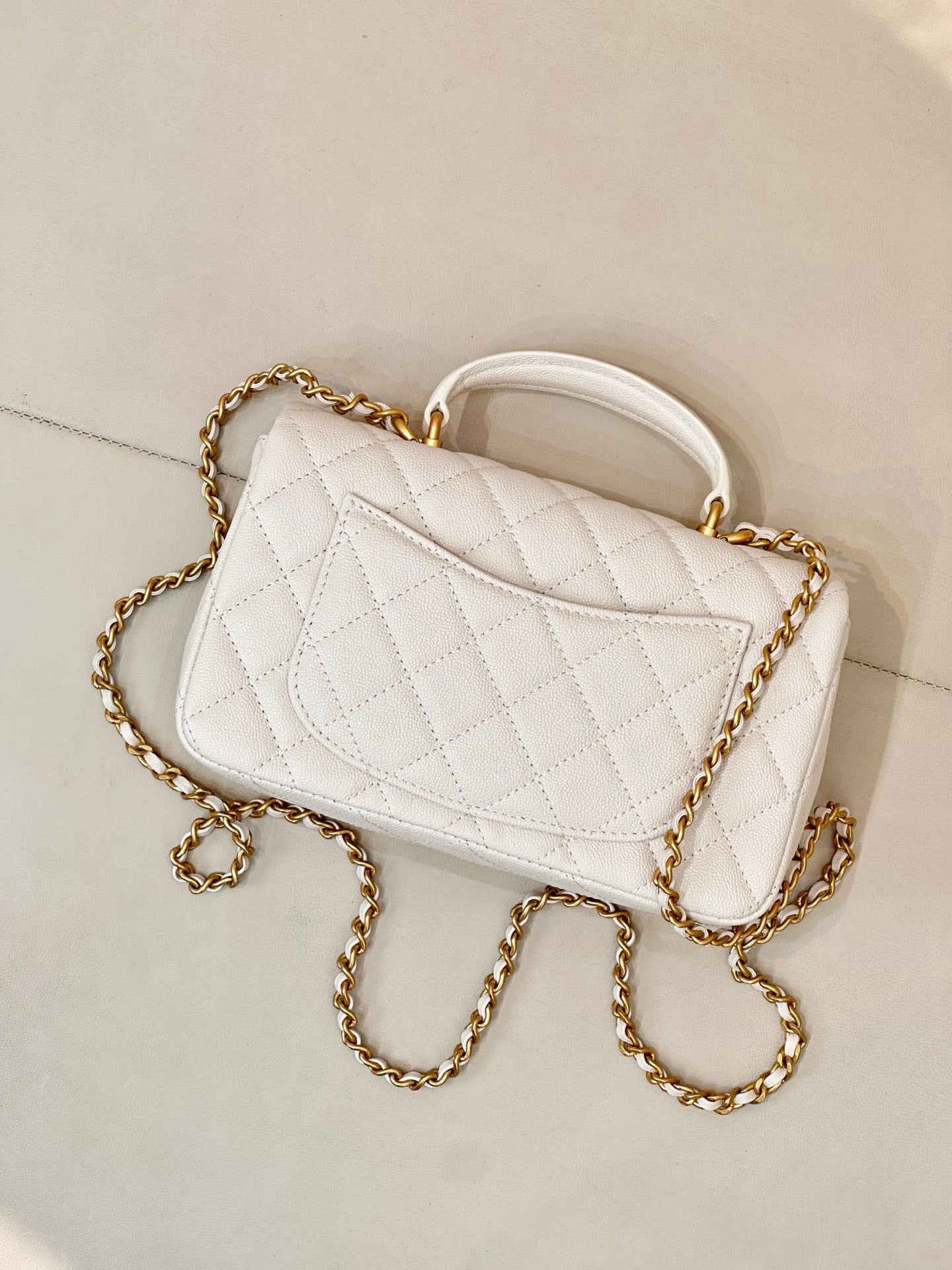 Chanel quilted mini flap bag angled view, white with gold chain strap and CC logo
