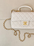 Chanel quilted mini flap bag front, white with CC logo on flap and gold chain