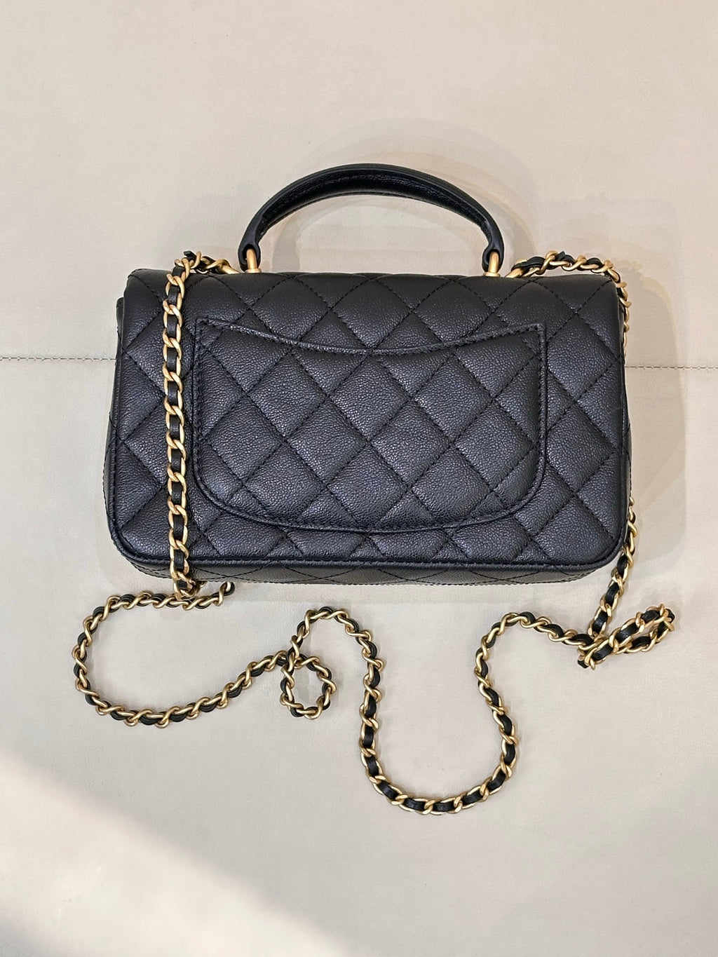 Chanel dark navy quilted flap bag with gold chain strap and top handle, angled view