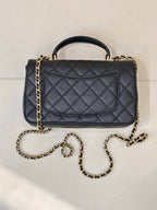 Chanel dark navy quilted flap bag with gold chain strap and top handle, angled view