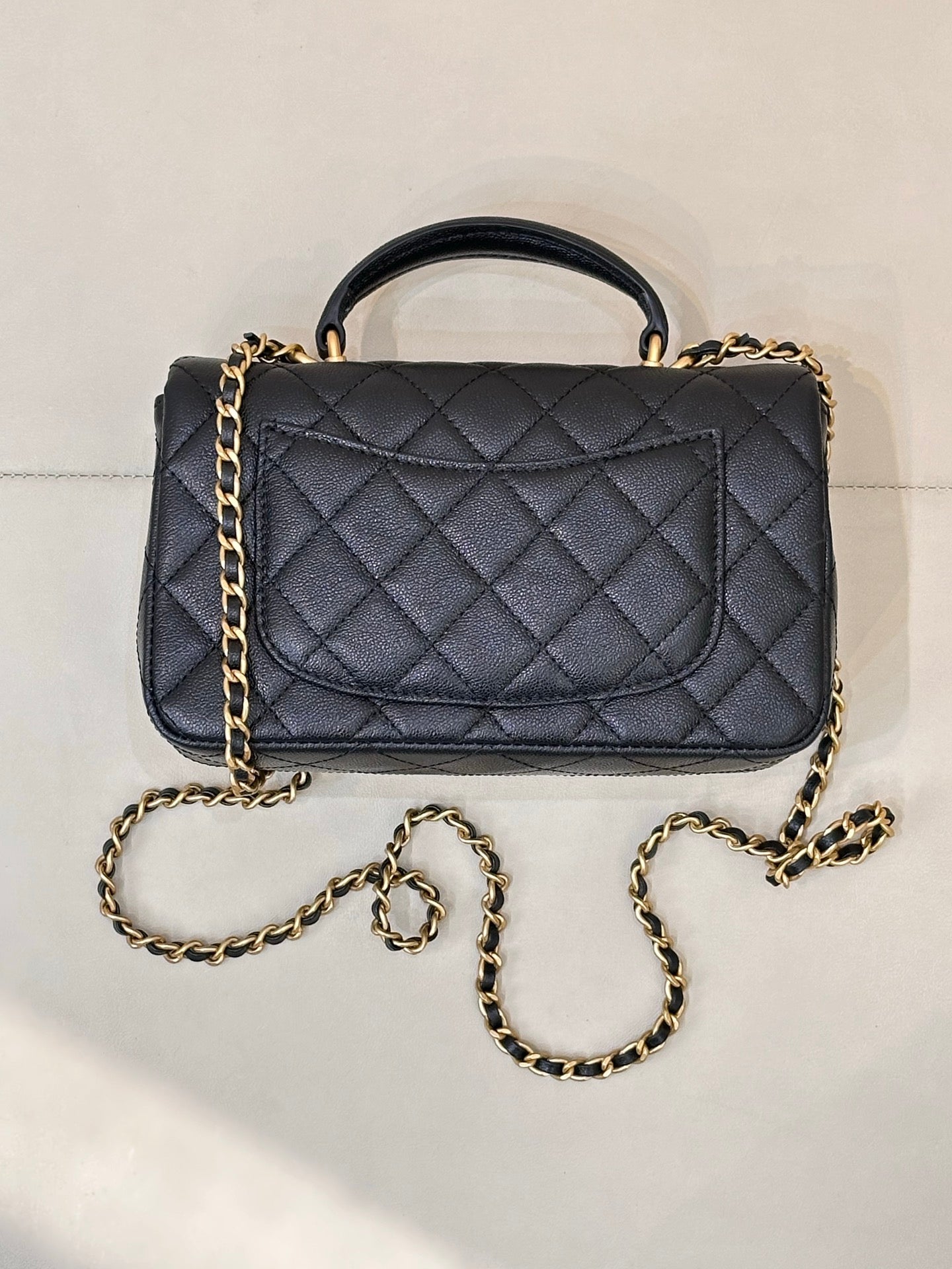 Chanel dark navy quilted flap bag with gold chain strap and top handle, angled view