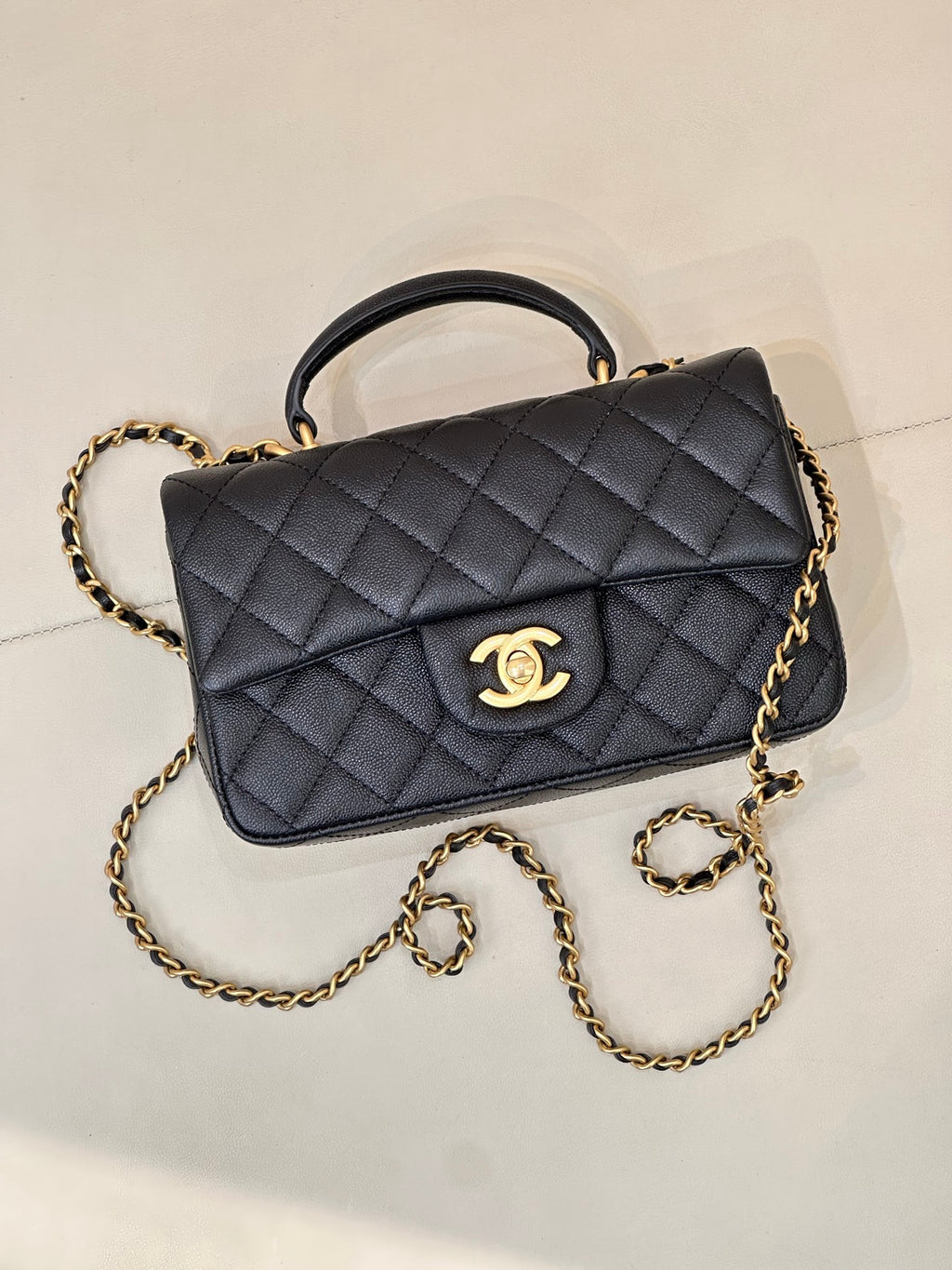 Chanel dark navy quilted flap bag with gold chain strap and curved top handle, logo