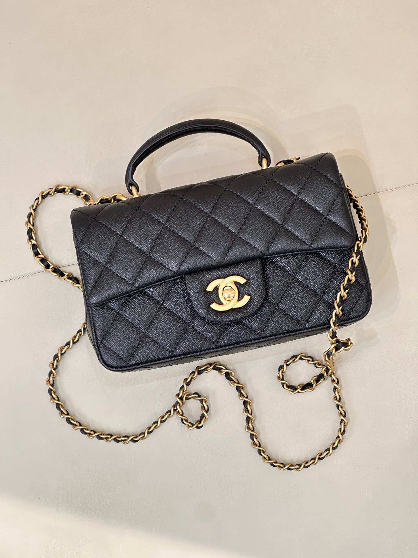 Chanel dark navy quilted flap bag with gold chain strap and curved top handle, logo