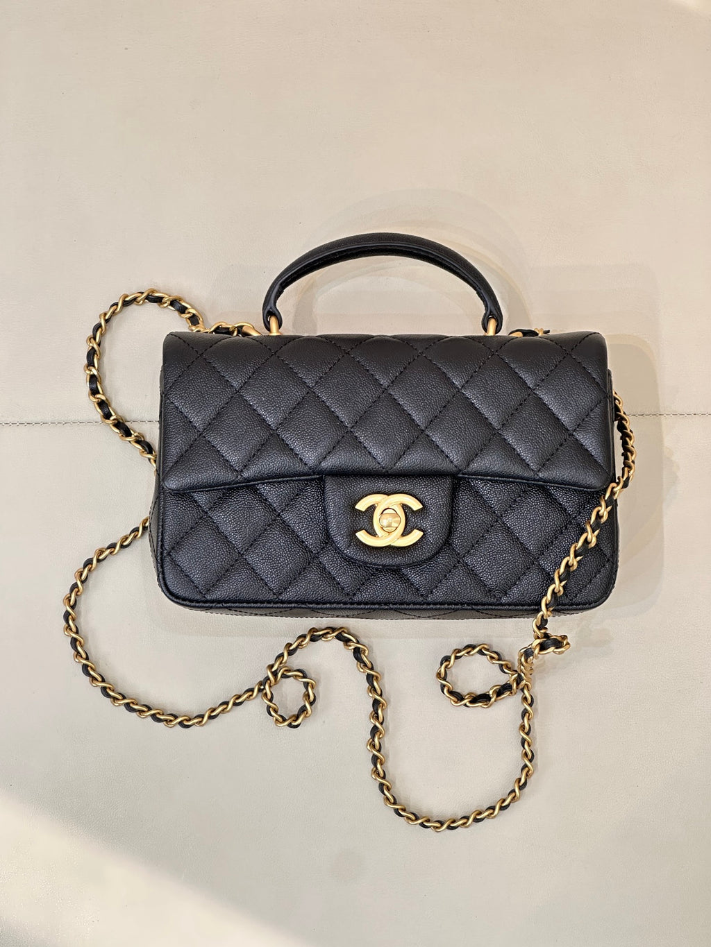 Chanel dark navy quilted flap bag with curved top handle and gold chain strap, logo