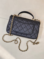 Chanel dark navy quilted flap bag with gold chain strap and curved top handle, side view