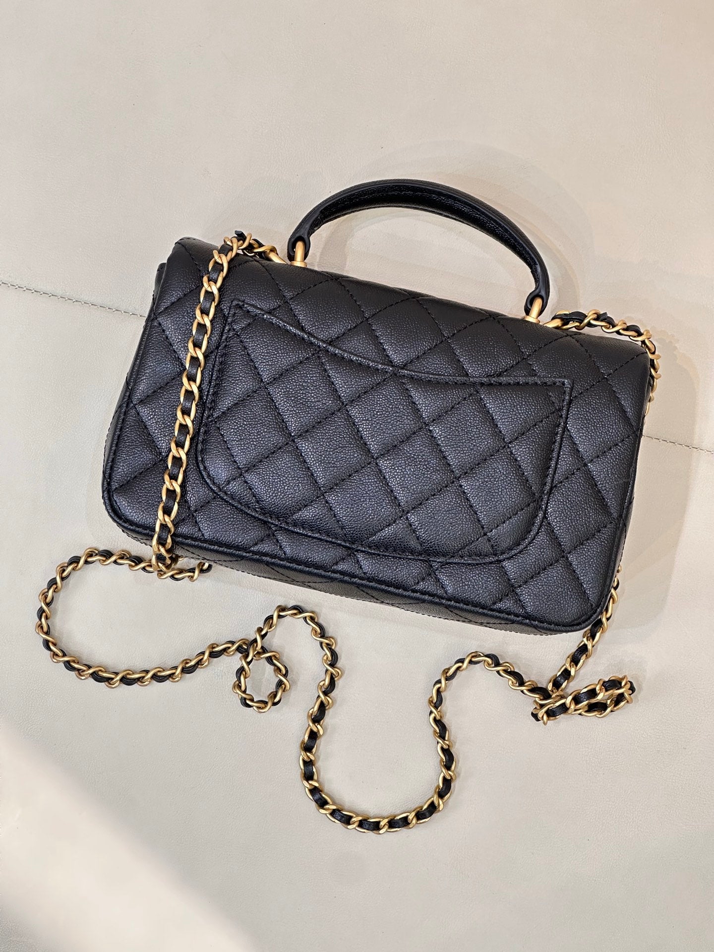 Chanel dark navy quilted flap bag with gold chain strap and curved top handle, side view