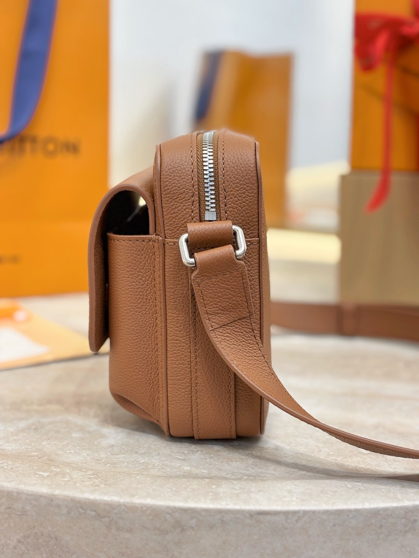 Tan leather Louis Vuitton bag with adjustable strap and side pocket opening