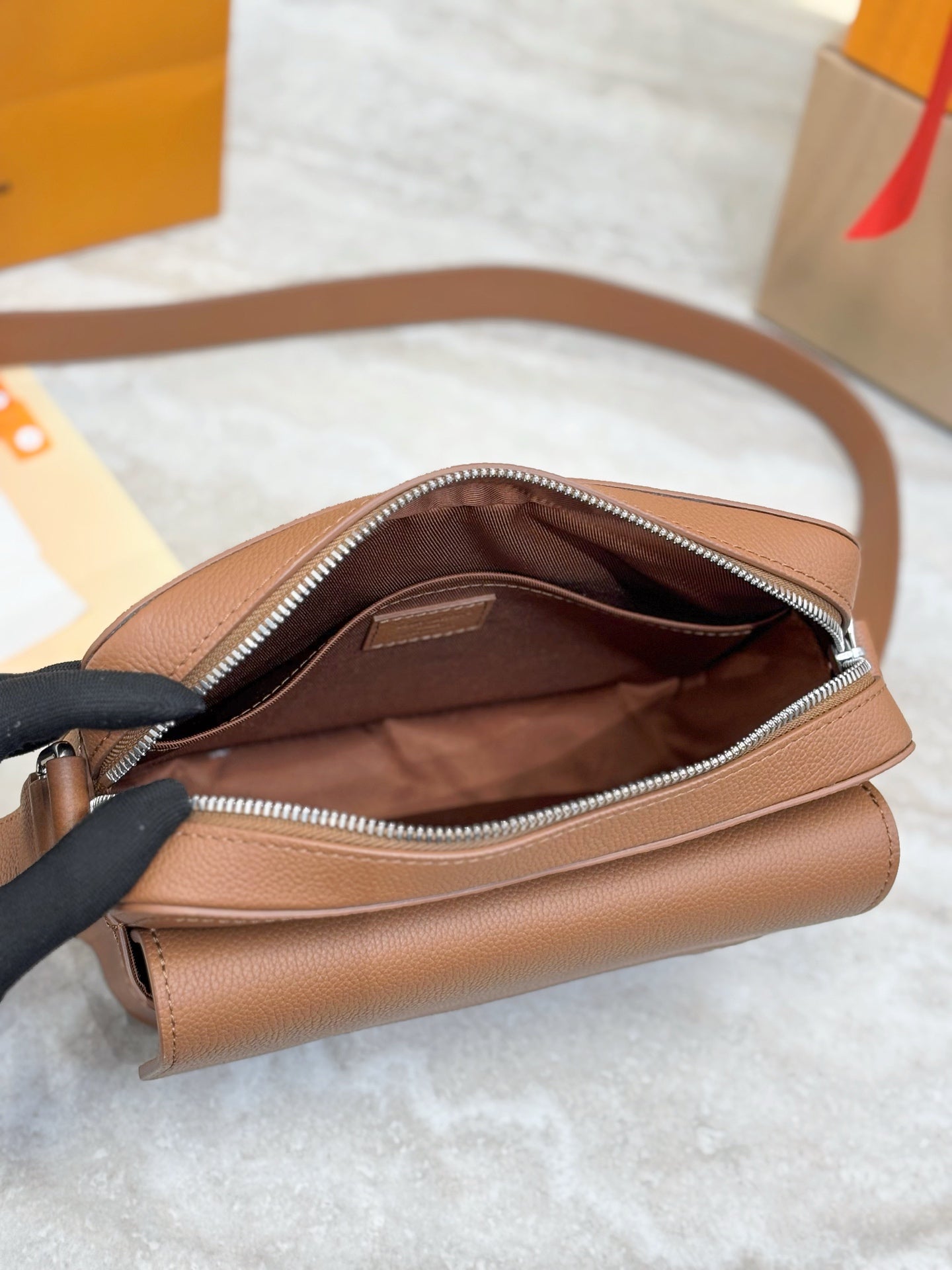 Tan leather Louis Vuitton crossbody bag with open top and zippered interior