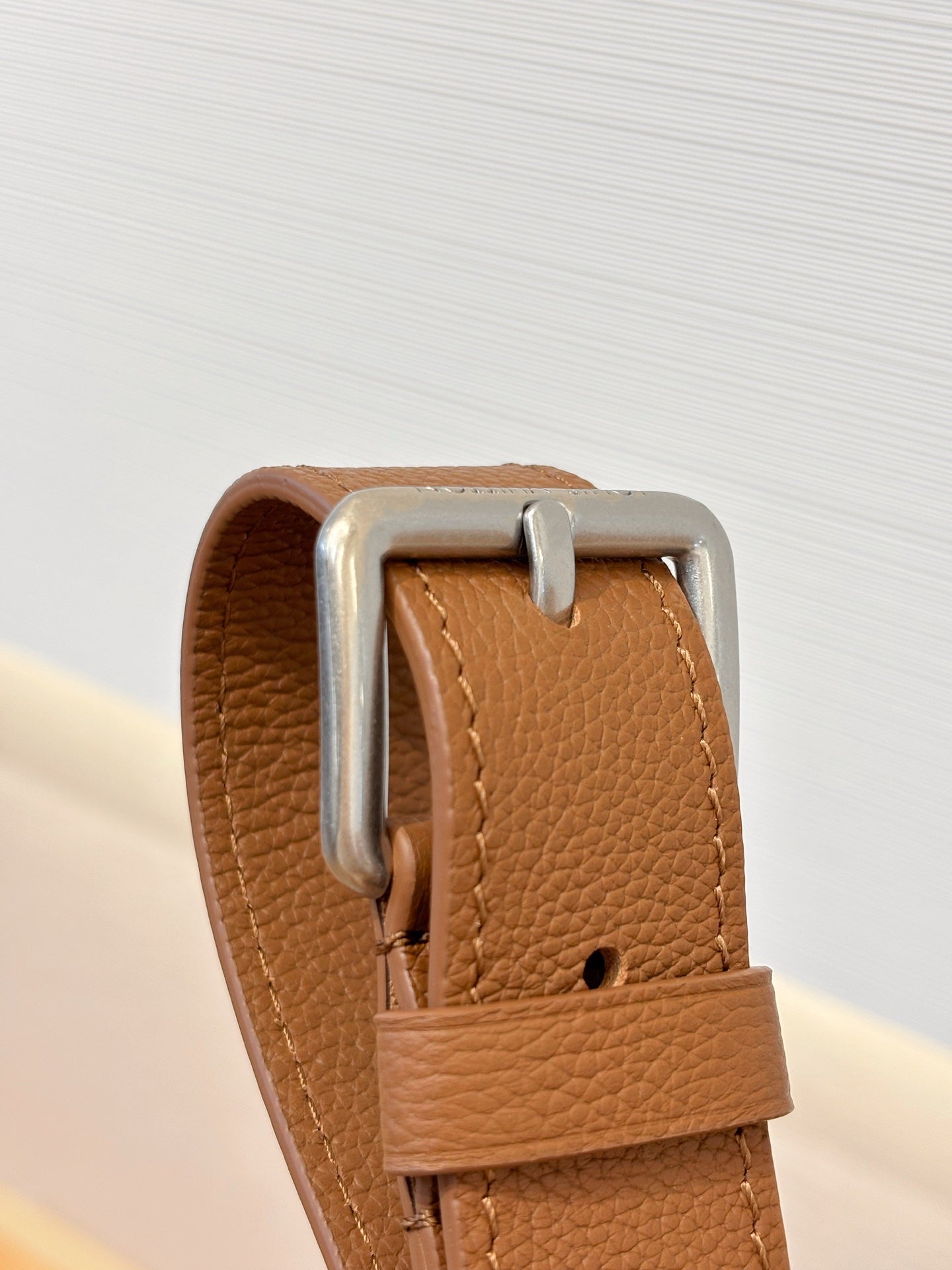 Close-up of tan leather Louis Vuitton strap with metal D-ring buckle