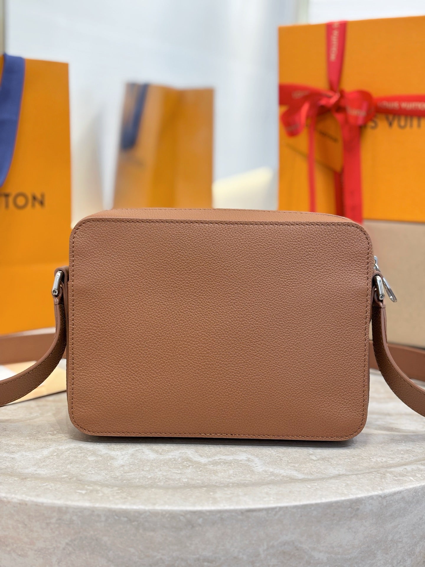 Tan leather Louis Vuitton crossbody bag from front view with flap and side buckles