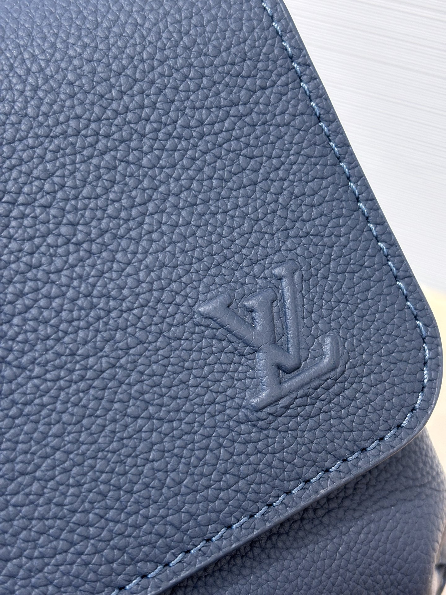 Louis Vuitton blue leather bag corner with embossed LV logo and stitched edge
