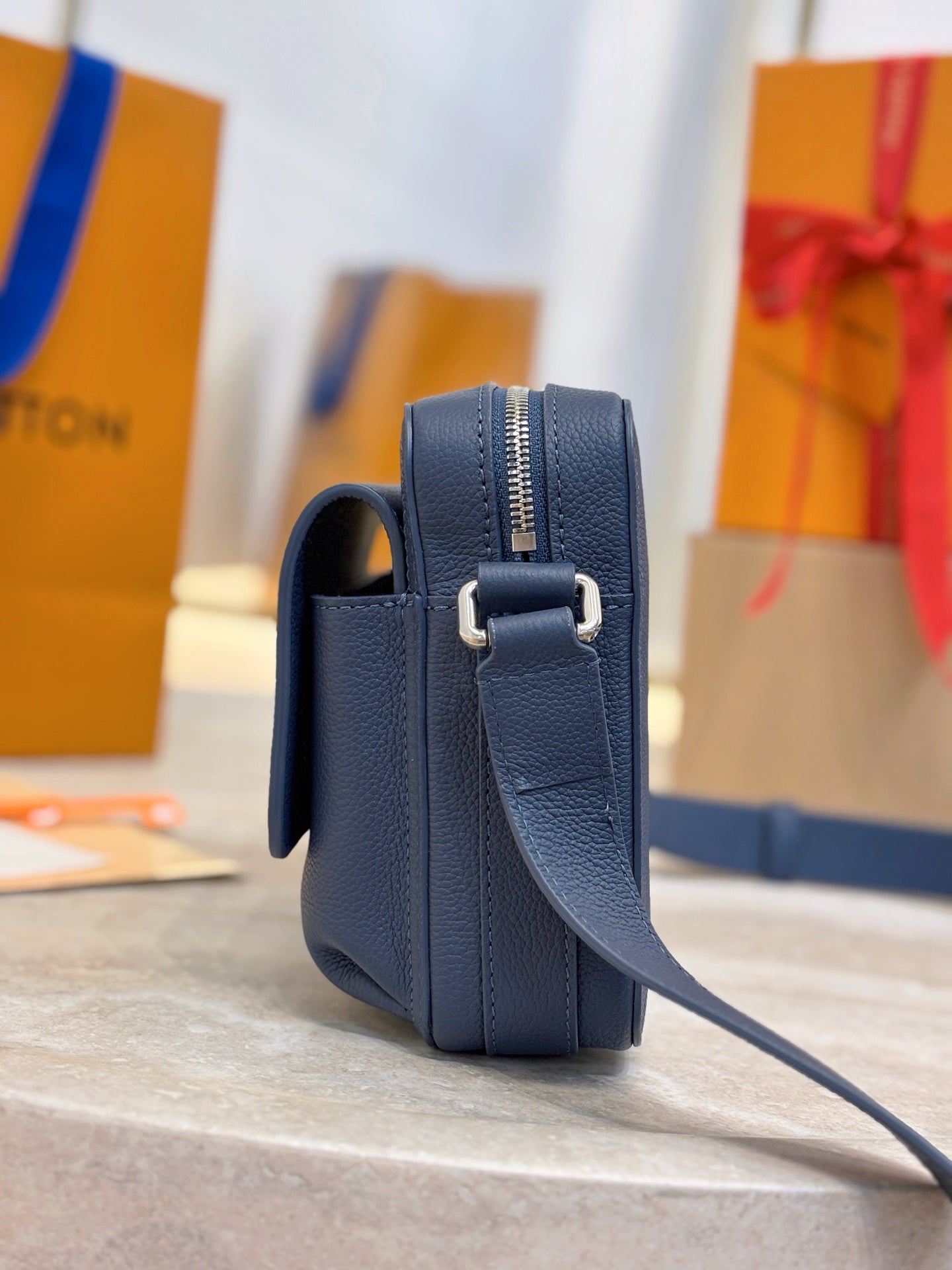 Louis Vuitton blue leather crossbody bag side view with zipper and strap loop