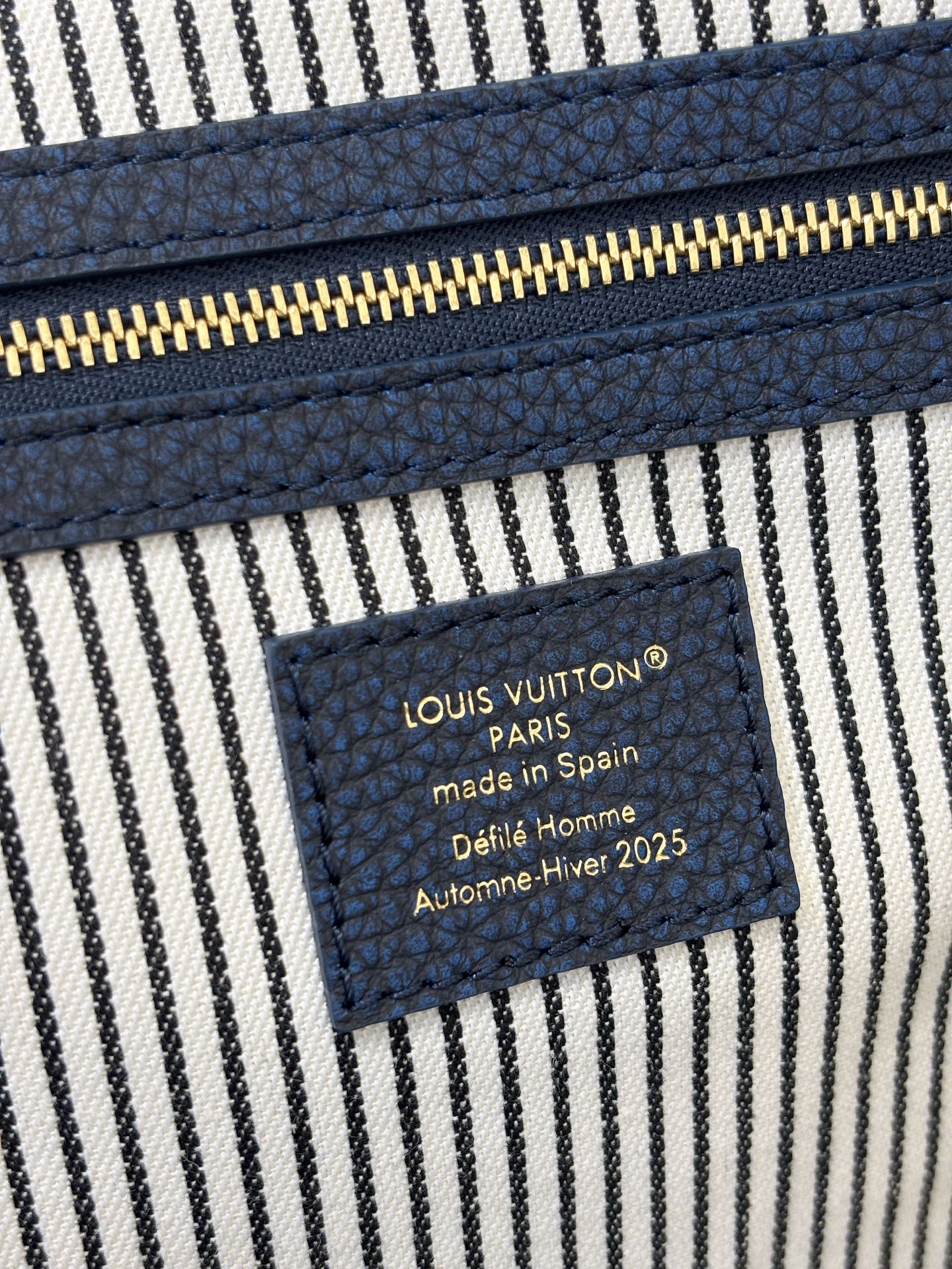 Louis Vuitton Paris label patch on striped interior lining of denim handbag