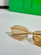Gold-frame sunglasses close-up with amber tint oval lens