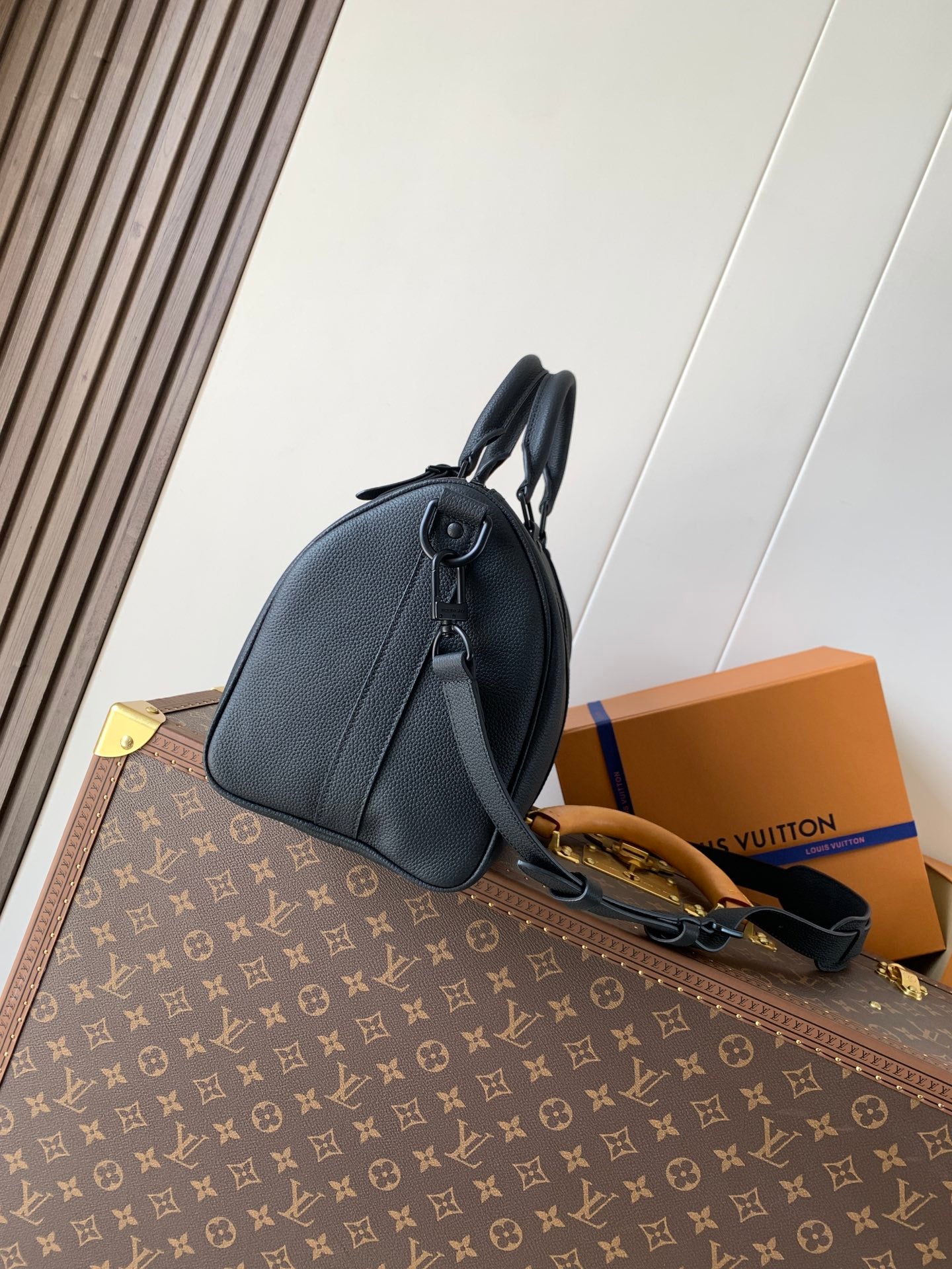 Dark blue leather men's duffel-style bag with curved top handle and adjustable strap