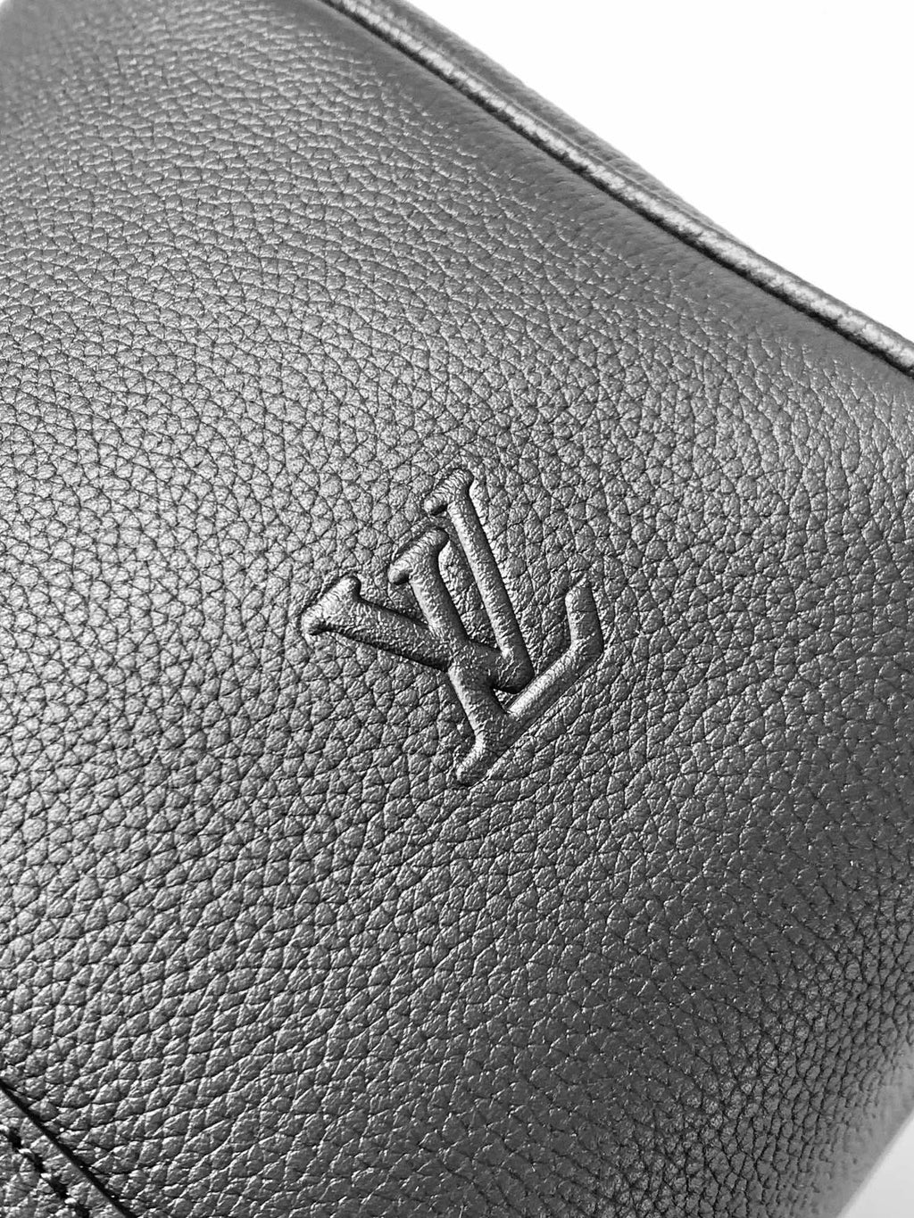 Textured dark leather panel with embossed Louis Vuitton logo
