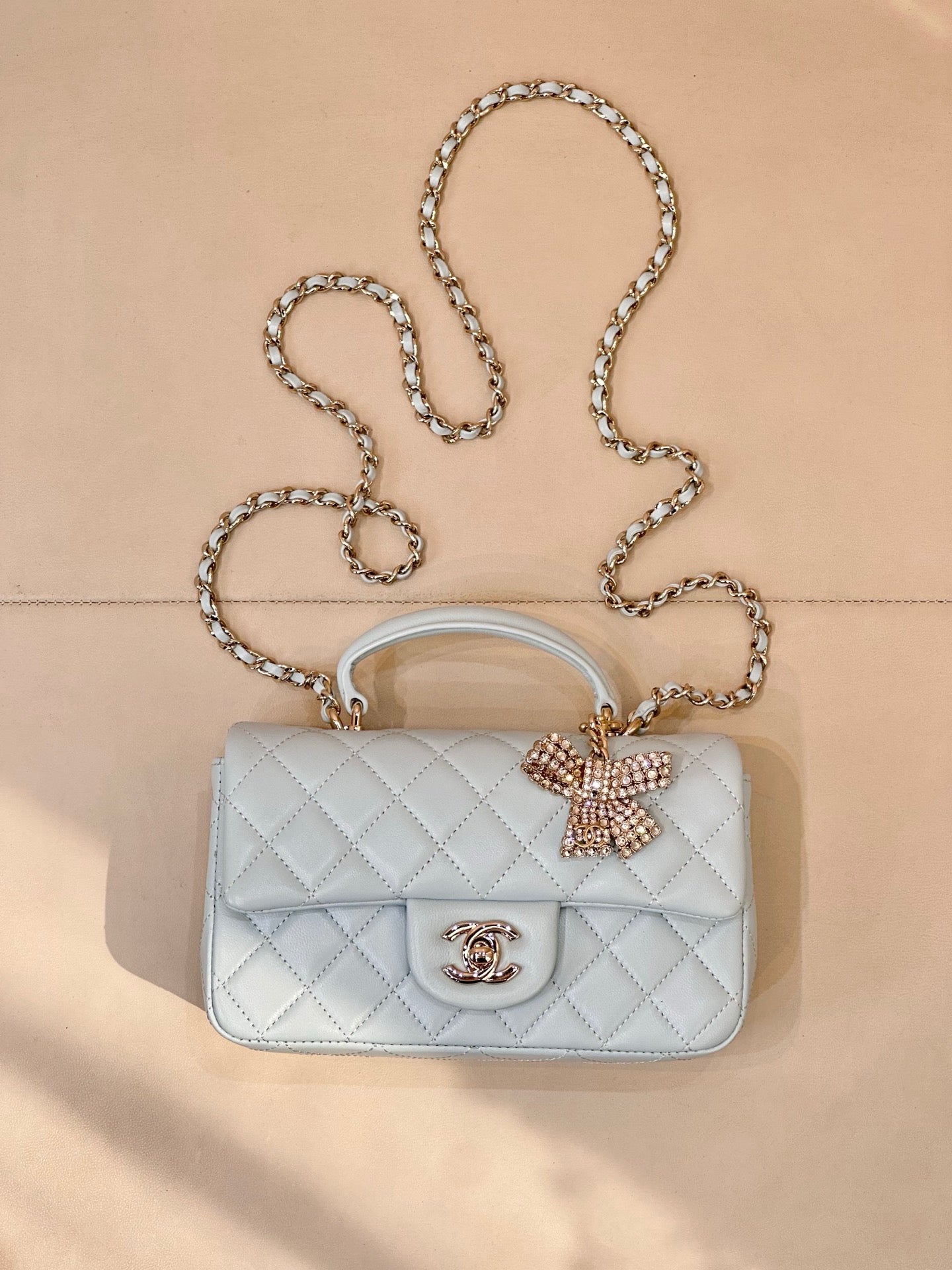 Light blue quilted handbag, flap with gold-tone logo, bow detail, chain strap