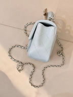 Light blue quilted mini handbag with gold-tone emblem, chain strap, small top handle