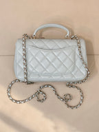 Light blue quilted handbag with front flap, gold-tone logo, chain shoulder strap