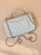 Light blue quilted handbag with front flap, gold-tone logo, chain strap, quilted pattern