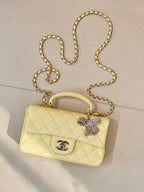 Light yellow quilted flap shoulder bag with gold chain strap and Chanel logo, bow charm.