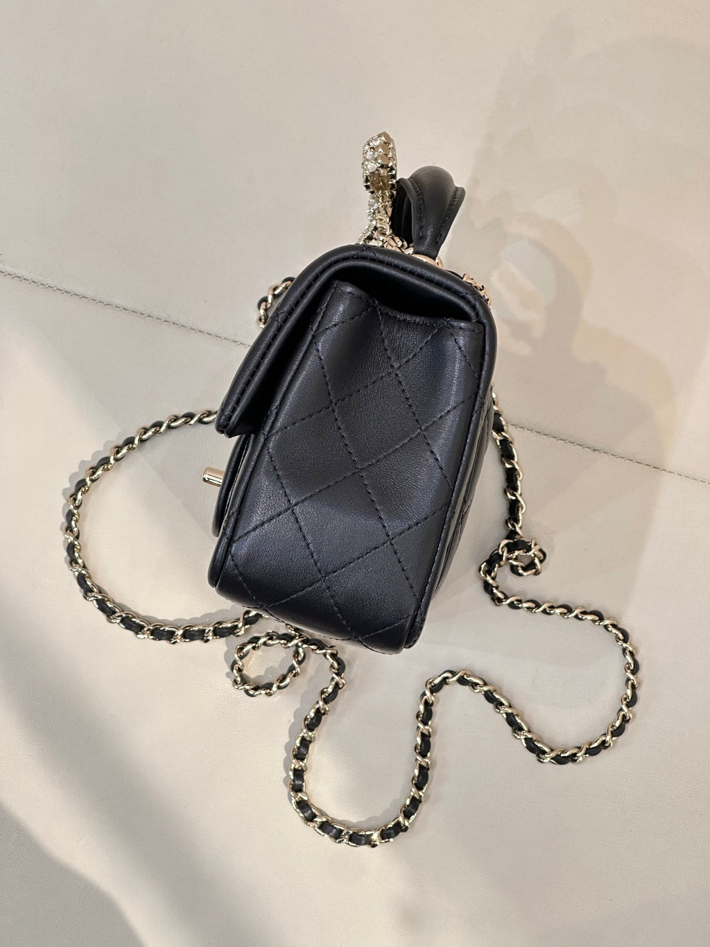 Dark small quilted leather crossbody bag with chain strap and top handle
