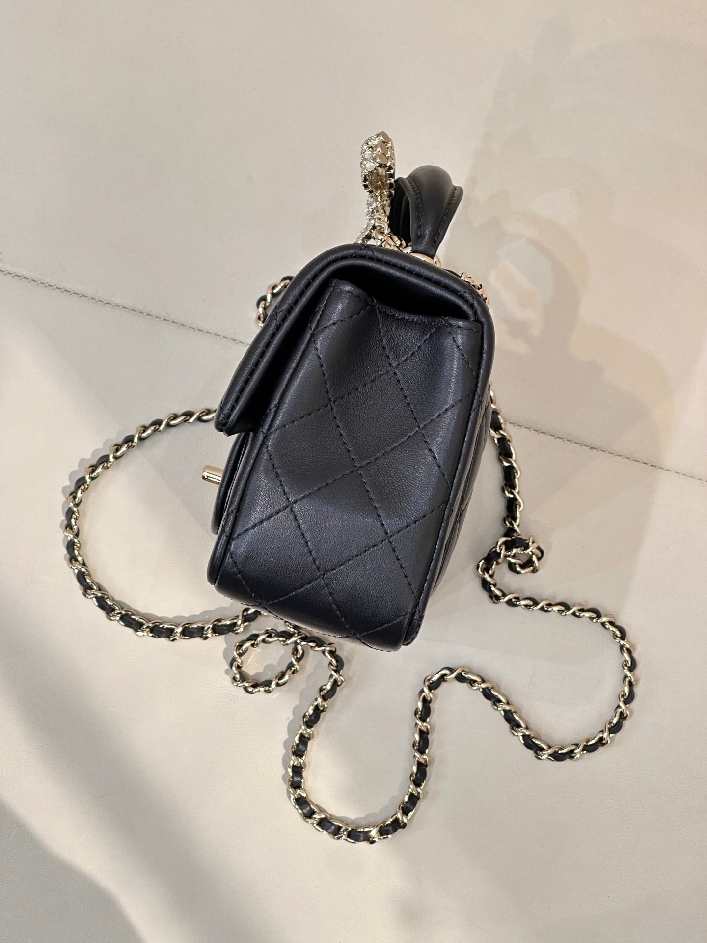 Dark small quilted leather crossbody bag with chain strap and top handle