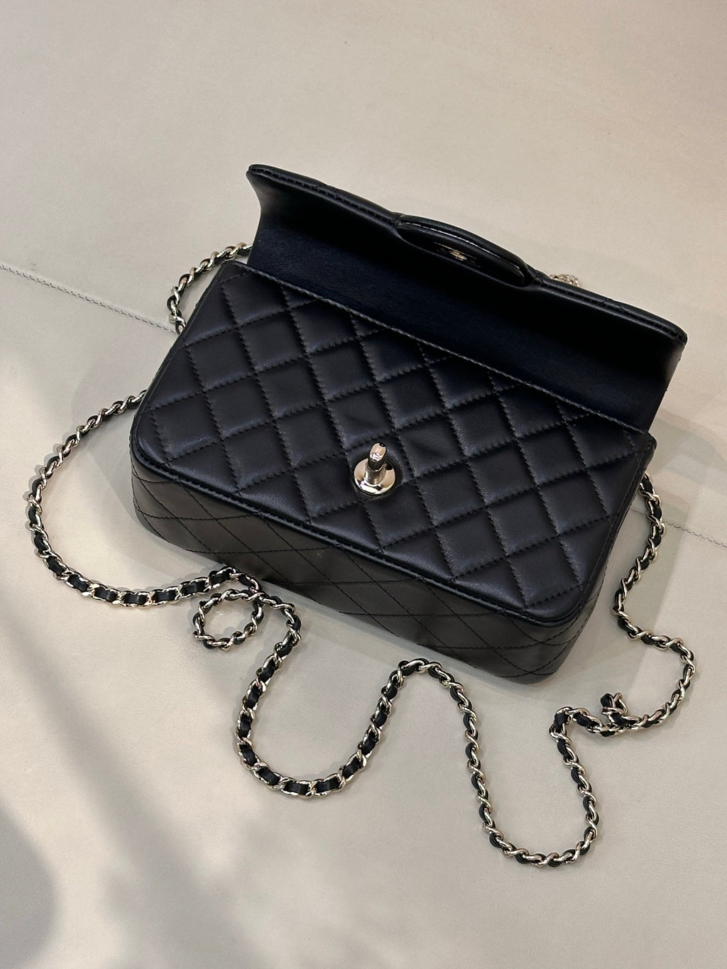 Dark quilted leather shoulder bag side view with gold-tone logo and chain strap