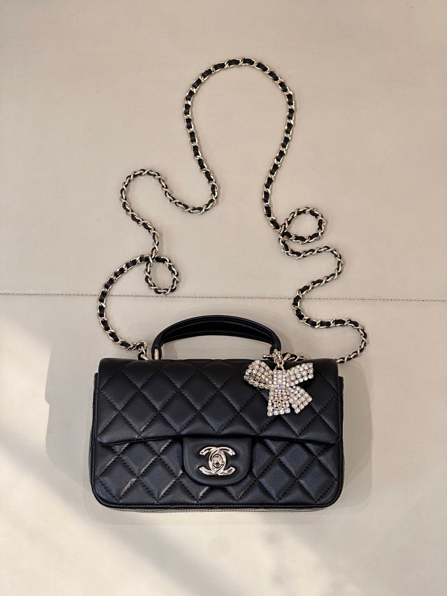 Dark quilted leather shoulder bag with chain strap and decorative bow clasp