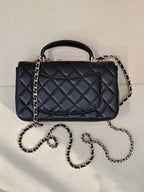Dark quilted leather flap handbag with top handle and chain shoulder straps