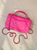 Chanel pink quilted handbag angled view with chain strap and top handle