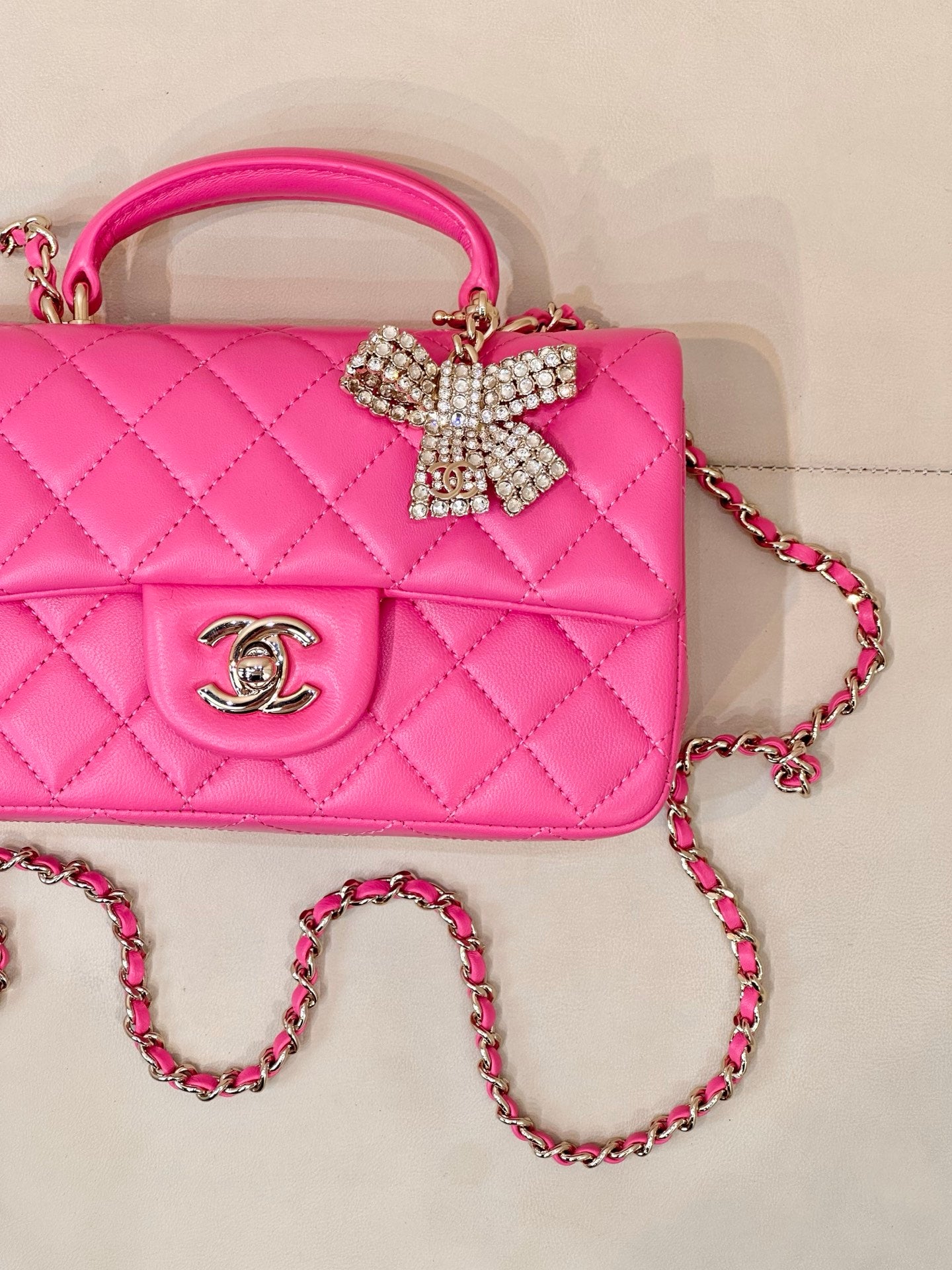 Chanel pink quilted bag with front emblem and rhinestone bow on top