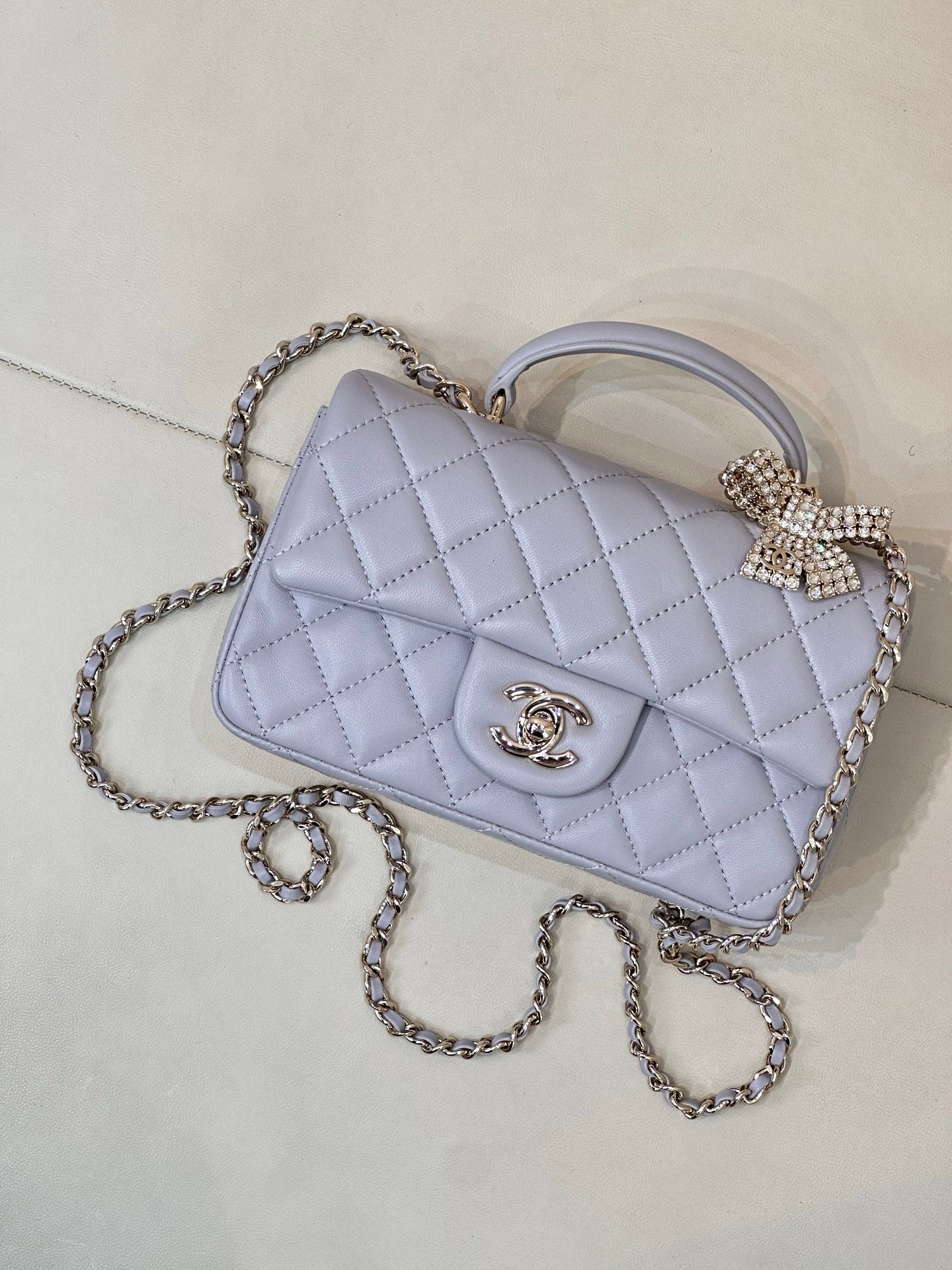 Quilted Chanel shoulder bag in light blue with diamond bow clasp and chain strap.