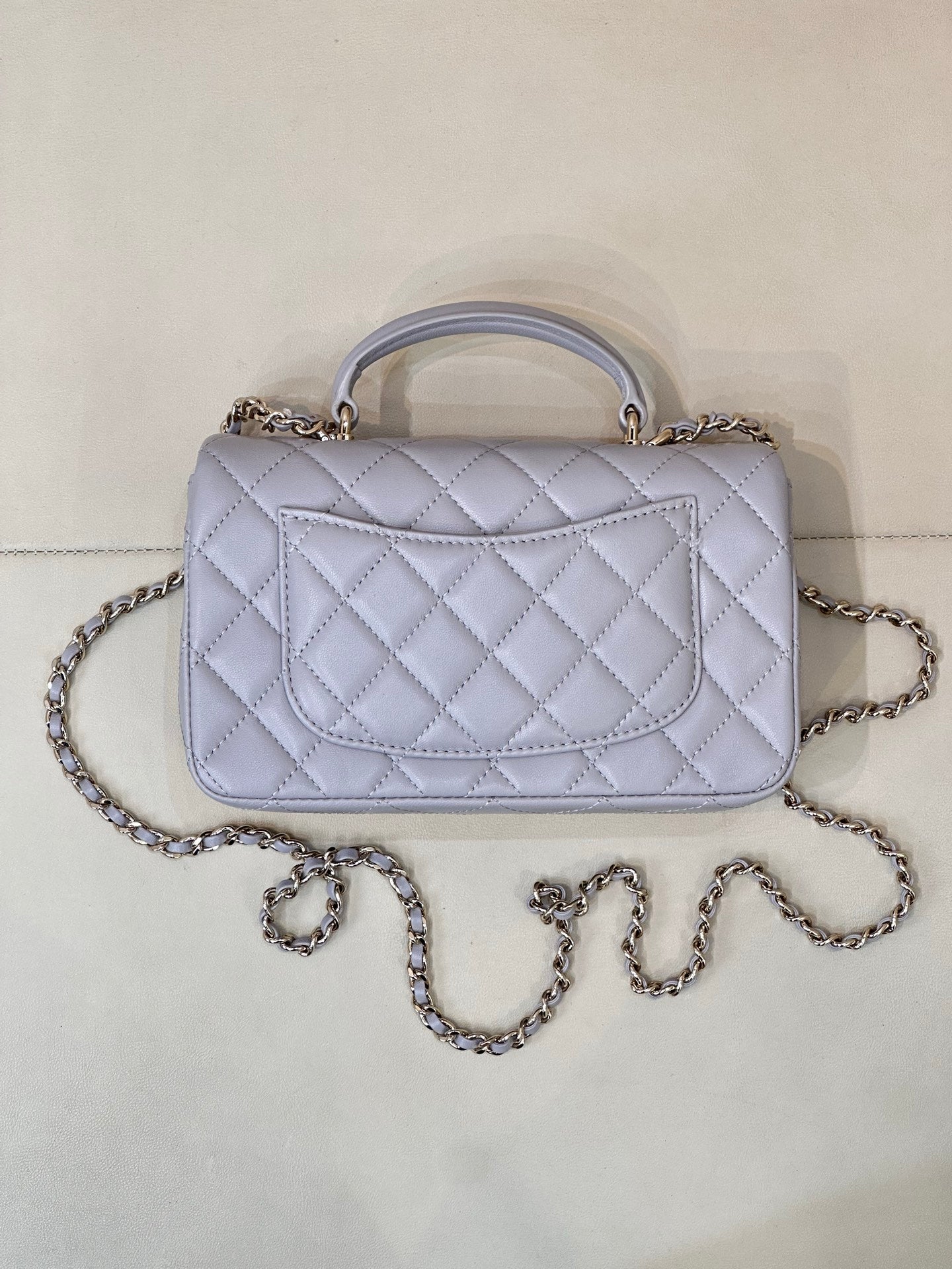 Light blue Chanel quilted top-handle shoulder bag with chain strap and clasp.
