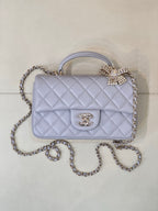 Quilted Chanel shoulder bag in light blue with flap, gold-tone logo, and chain strap.