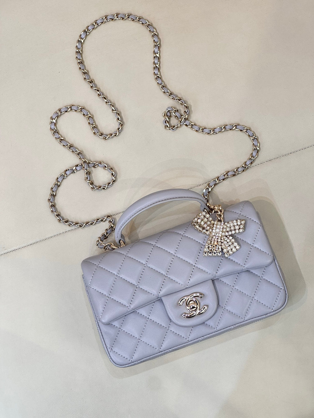 Light blue Chanel quilted crossbody bag with rhinestone bow and gold-tone CC logo.