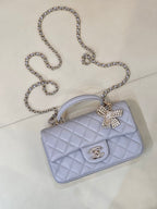 Light blue Chanel quilted crossbody bag with rhinestone bow and gold-tone CC logo.