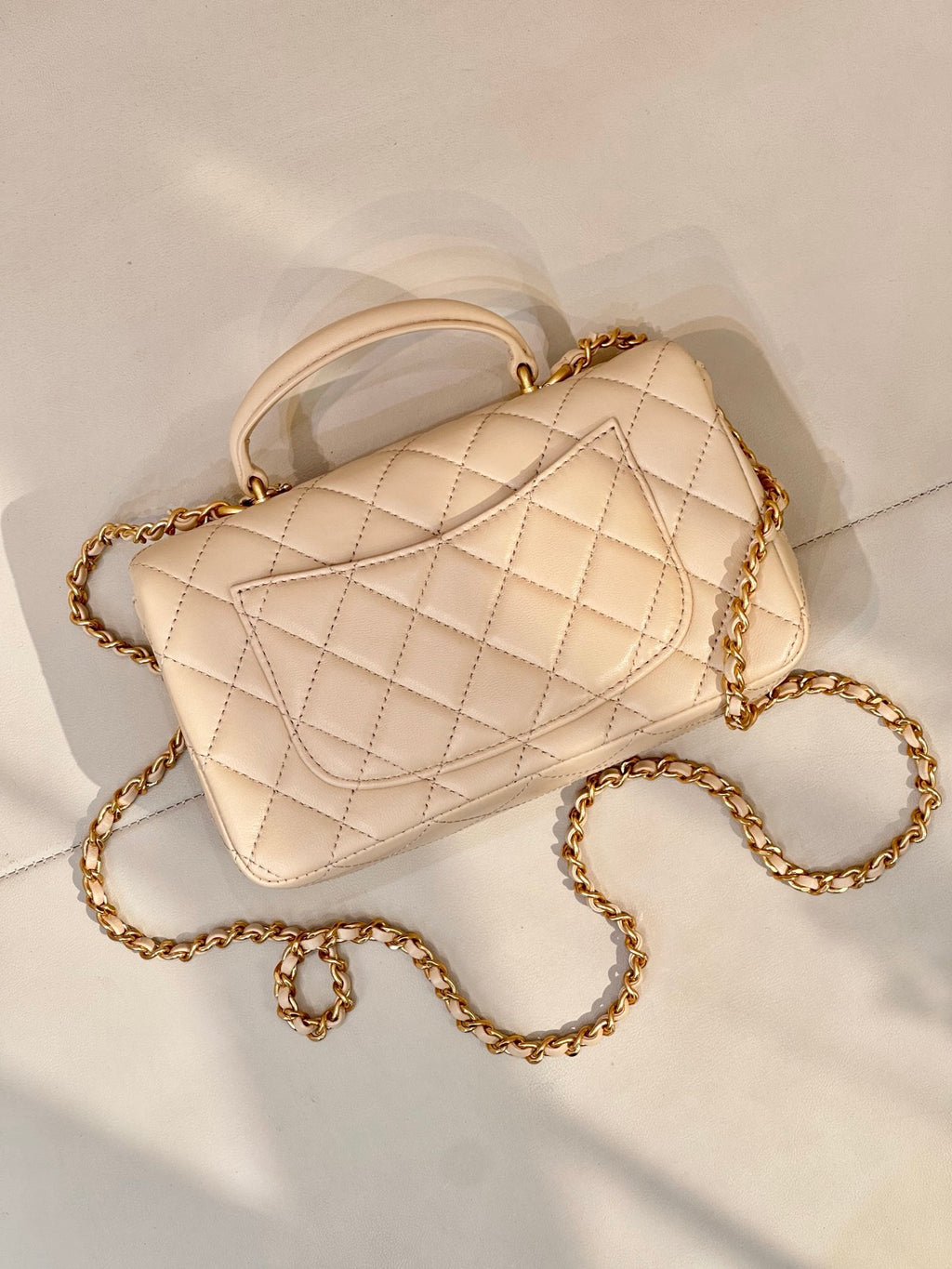 Chanel quilted leather shoulder bag with chain strap and logo flap in light beige, angled view