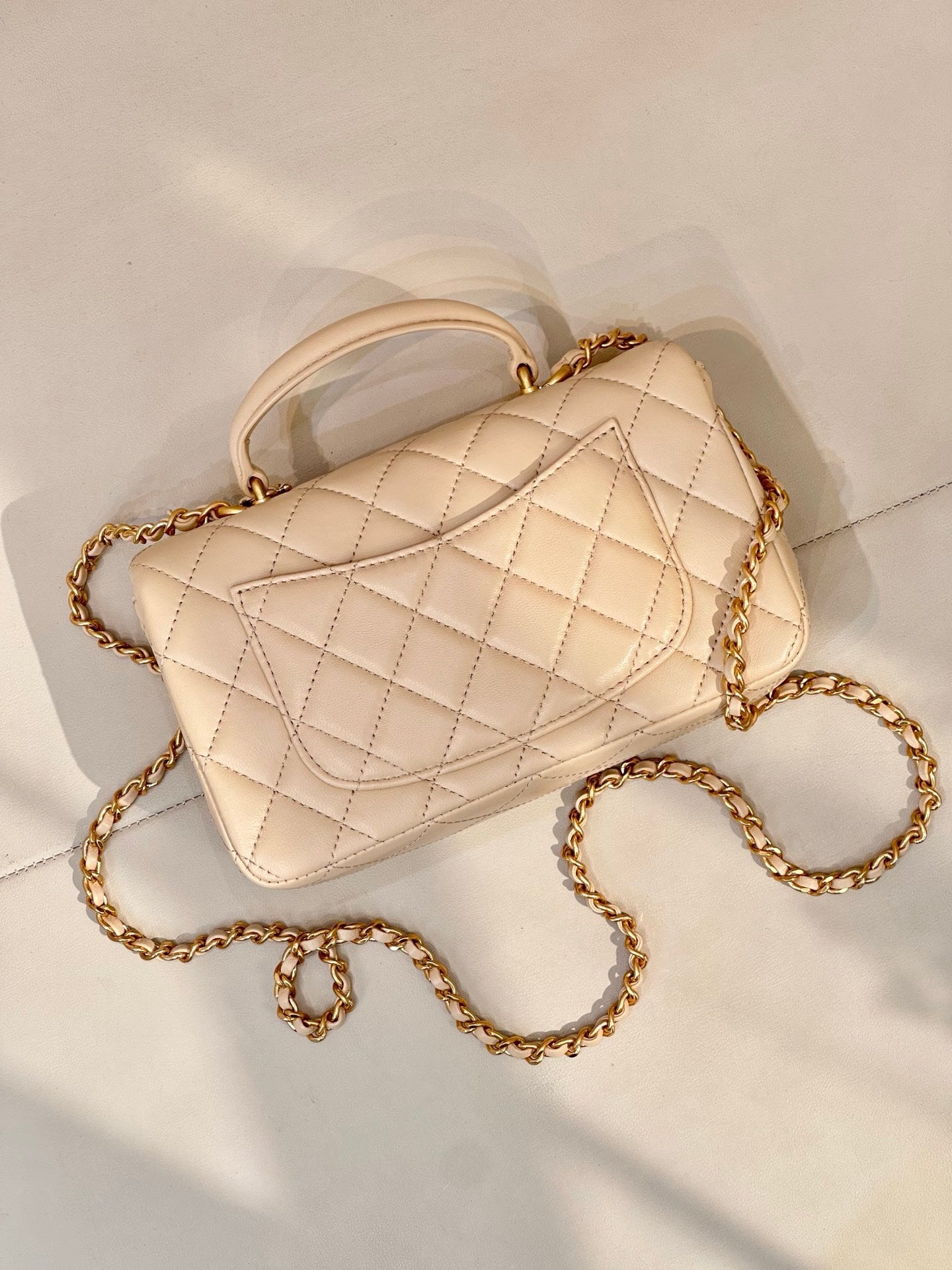 Chanel quilted leather shoulder bag with chain strap and logo flap in light beige, angled view