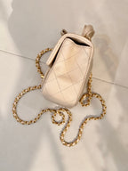 Chanel quilted leather bag with chain strap and top handle in light beige, side view
