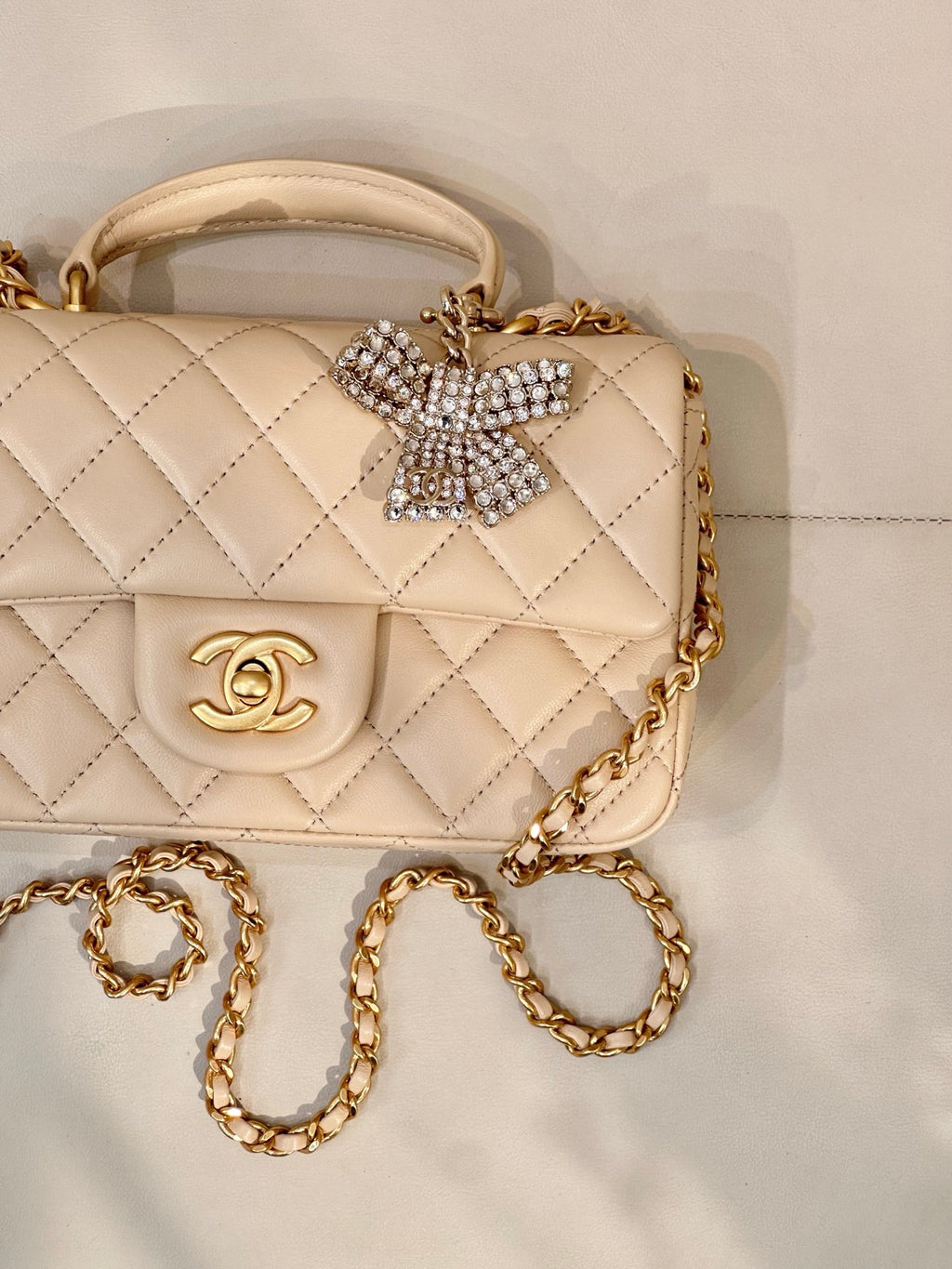 Chanel quilted leather bag close-up with logo flap, crystal bow detail, and gold chain strap