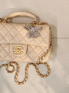 Chanel quilted leather bag close-up with logo flap, crystal bow detail, and gold chain strap