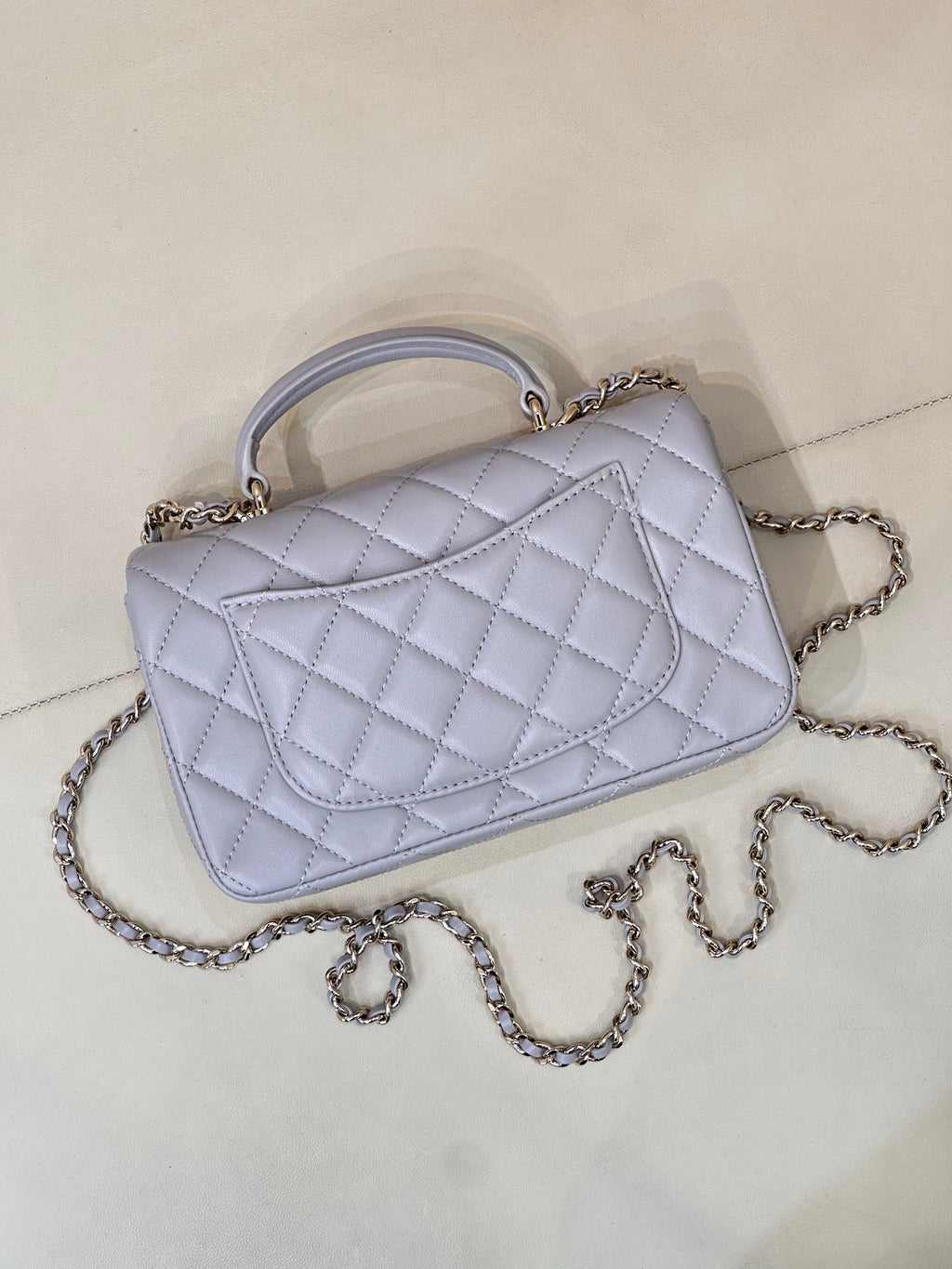 Light blue Chanel quilted shoulder bag with curved flap, chain strap, and gold-tone clasp.