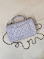 Light blue Chanel quilted shoulder bag with curved flap, chain strap, and gold-tone clasp.